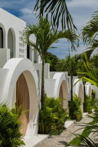 un edificio blanco con palmeras en un patio en The Makara Villas Uluwatu, en Uluwatu
