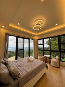 a bedroom with a bed and large windows at The Hillside Villa Tagaytay in Laurel
