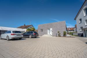 two cars parked in a parking lot in front of a building at JULI-Homes - Self Check-In Studios mit Küche am Bodensee & Spieleland in Meckenbeuren