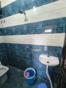 uma casa de banho em azulejos azuis com um lavatório e um balde em Parth homstay em Ayodhya