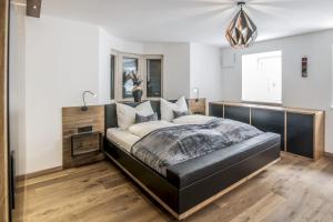 a bedroom with a bed with a black leather headboard at Stylish Alpine Apartment with Terrace, Fireplace & Mountain View near Sterzing - Villa Tribulaunblick in Colle Isarco