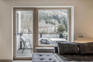 a living room with a couch and a large window at Stylish Alpine Apartment with Terrace, Fireplace & Mountain View near Sterzing - Villa Tribulaunblick in Colle Isarco +49 photos