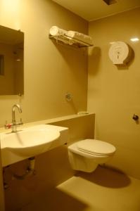 a bathroom with a sink and a toilet and a mirror at Prithvi Hotels in Ahmedabad
