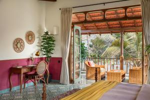 a bedroom with a balcony with a bed and a desk at Villa Fado - 4BHK Luxury Villa with Big Private Pool, Kitchen, Balcony, Patio, Caretaker, Power Backup, Security & WiFi located closer to Vagator Beach in Assagao