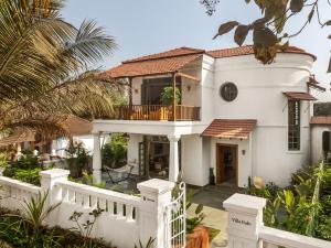 a white house with a porch and a balcony at Villa Fado - 4BHK Villa with Private Pool in Assagao, Kitchen, Caretaker in Assagao