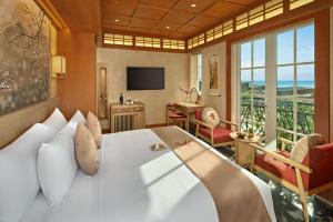 a bedroom with a large white bed and a living room at Sakurakyo Hotel & Spa Phu Quoc - Free Hon Thom Island Waterpark Cable Car Until 15 December 2025 in Phu Quoc