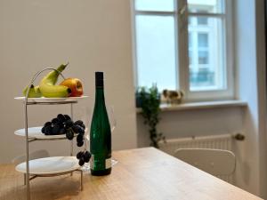 a bottle of wine sitting on a table with a plate of fruit at Gemütliches Apartment im Zentrum Andernach in Andernach