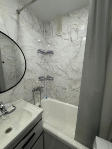 ein Badezimmer mit einer weißen Badewanne, einem Waschbecken und einem Spiegel in der Unterkunft Уютные 1комнатные апартаменты на Казииту in Oral + 9 Fotos