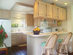 プリンスビルにあるSpacious Getaway Condo Near Beach & Golf 1st Floorのキッチン(木製キャビネット、カウンターのスツール2脚付)