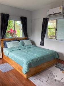 a bedroom with a bed with a green comforter and two windows at Seasalt 1 Cozy Studio with Full kitchen and fast WiFi in Thong Sala