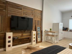 a living room with a television on a wooden wall at South West Rocks Gap Beach Studio in Arakoon