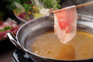 a piece of ham being dipped into a pot of food at GRANDVRIORESORT ISHIGAKIJIMA Ocean's Wing & Villa Garden in Ishigaki Island