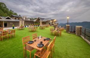 a patio with tables and chairs on the grass at Royal Apartments Kasauli I Restaurant I Lift I Roof top Cafe I Self cooking also available I Bonfire I Best View in Kasauli