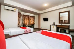 a hotel room with two beds and a mirror at Dancenter JA Siam City in Pattaya