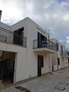 a white building with two balconies and a courtyard at Relax beach San Vito lo Capo in San Vito lo Capo