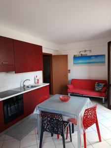 a kitchen with a table and a red couch at Relax beach San Vito lo Capo in San Vito lo Capo