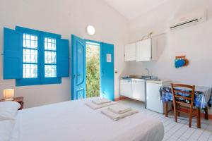 a room with a bed and a kitchen with blue doors at Agriturismo Costa del Sud in Teulada