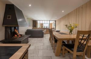a kitchen with a fireplace and a dining room with a table at Ferme de Bellevue in Longevilles-Mont-dʼOr