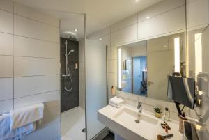 une salle de bain avec un lavabo, une douche et un miroir dans l'établissement Mercure Bords de Loire Saumur, à Saumur