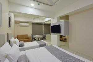 a hotel room with two beds and a flat screen tv at HOTEL SHALIGRAM in Ahmedabad