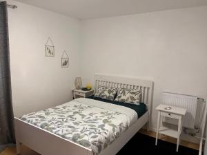 a white bedroom with a bed and two tables at 2 Superbes chambres d hôte dans un appartement avec magnifique vue sur Paris in Sucy-en-Brie