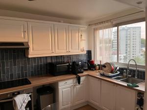 a kitchen with white cabinets and a sink and a window at 2 Superbes chambres d hôte dans un appartement avec magnifique vue sur Paris in Sucy-en-Brie