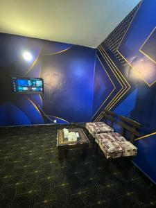 a room with a blue wall with a couch and a table at Hotel Hayat Palace Johar Town in Lahore