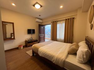 a bedroom with a bed and a large window at Lhamhendo Retreat in Mārkhu