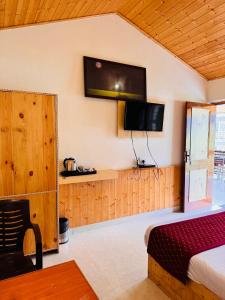 a bedroom with a bed and a tv on the wall at KEYAAN STAYS in Manāli +63 photos