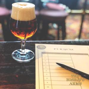 a glass of beer sitting on a table next to a paper at Hotel Bishops Arms Mora in Mora