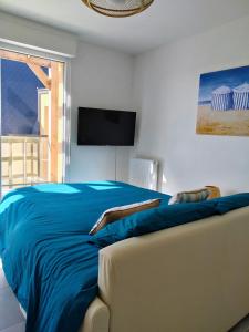 a bedroom with a blue bed and a couch at Appartement neuf, calme et ensoleillé in Cabourg +14 photos