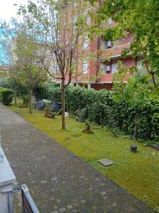 Un jardín con un árbol en el césped al lado de un edificio. en casa vacanze Lida, en Marina di Carrara