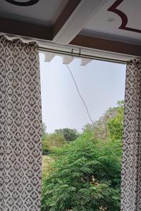 FaizābādShri Balaji Home Stay的一扇挂着窗帘的窗户和一棵树