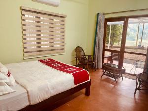 a bedroom with a bed and a window and chairs at The River House in Cochin