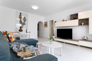 a living room with a blue couch and a tv at Casa Queen Vetusta -Pool and Tennis in Arrecife