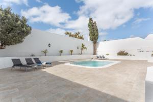 a patio with a pool and chairs and a white wall at Casa Queen Vetusta -Pool and Tennis in Arrecife