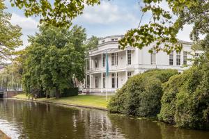 een groot wit huis aan de oever van een rivier bij BizStay Maurits in Den Haag