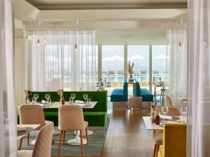 a restaurant with tables and chairs and windows at Sofitel Golfe d'Ajaccio Thalassa Sea & Spa in Ajaccio