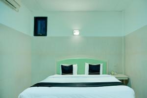 een slaapkamer met een groot wit bed met 2 blauwe kussens bij Dancenterak Palembang Near Jembatan Ampera Formerly Azzura Hotel in Palembang +25 foto's