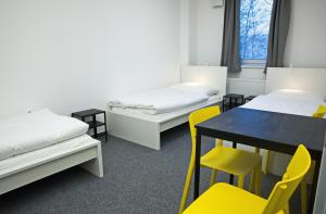 una camera con due letti e un tavolo con sedie gialle di Hostel Optimum Devínska a Devin