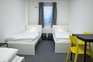 una camera con due letti e un tavolo con sedie gialle di Hostel Optimum Devínska a Devin