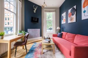 Una sala de estar con un sofá rojo y una mesa. en Sunny Corner Apartment in Center of London (1), en Londres