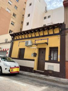 een witte auto geparkeerd voor een geel gebouw bij House in Malaga in Málaga