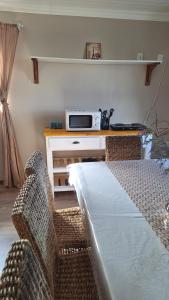a bedroom with two chairs and a table with a microwave at Nature's View - Dana Bay in Mossel Bay