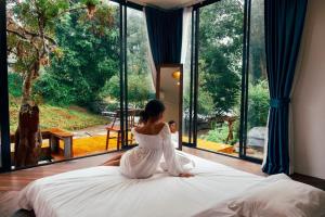 Ban Mae Sapok Noi3pok-Riverside maewangjinxiang的坐在床上的女人穿着白色的衣服