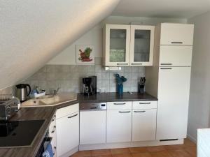 a kitchen with white cabinets and a sink at Eastside-Apartment WHG 01 in Senftenberg +7 photos