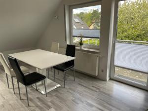 a white table and chairs in a room with two windows at Eastside-Apartment WHG 01 in Senftenberg