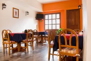 a dining room with tables and chairs and orange walls at OYO Hotel Museo in Xalapa