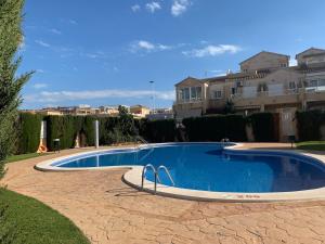 a large swimming pool in a yard with houses at Charming duplex with pool in Torrevieja