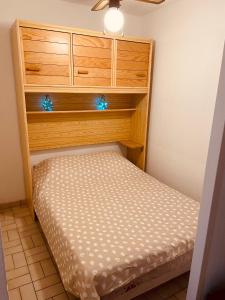 Cama pequeña en habitación con armario de madera en Le Palm Beach vue mer le Barcares, en Le Barcarès